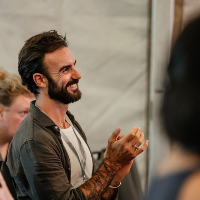 Julian, Talent Partner, smiling while applauding at an event
